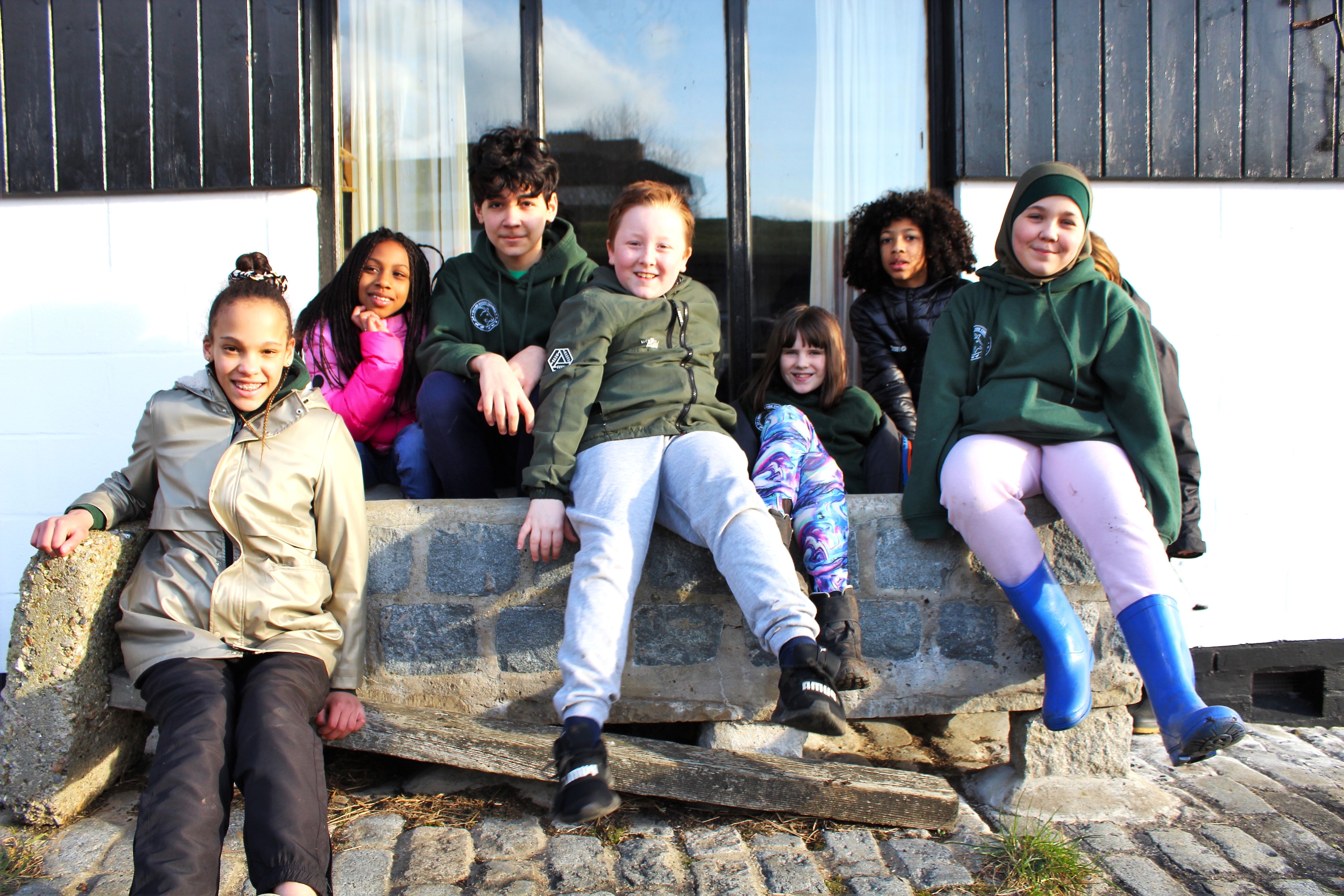 A group of Young Farmers sit in a water trough and smile 