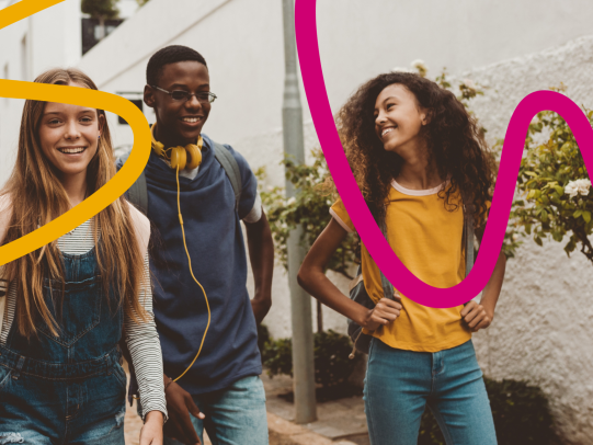 Three young people walking together, smiling and chatting on a sunny day